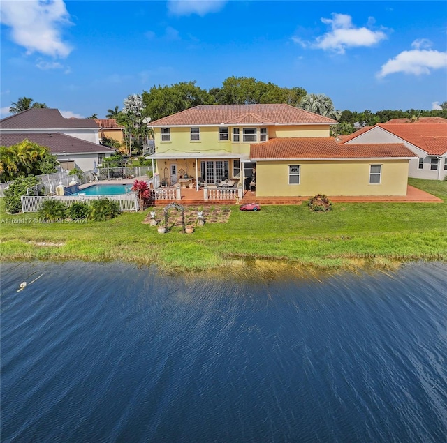 rear view of house with a lawn, a water view, and a patio