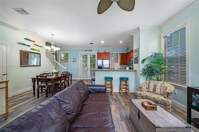 living room featuring ceiling fan with notable chandelier, dark hardwood / wood-style flooring, and ornamental molding