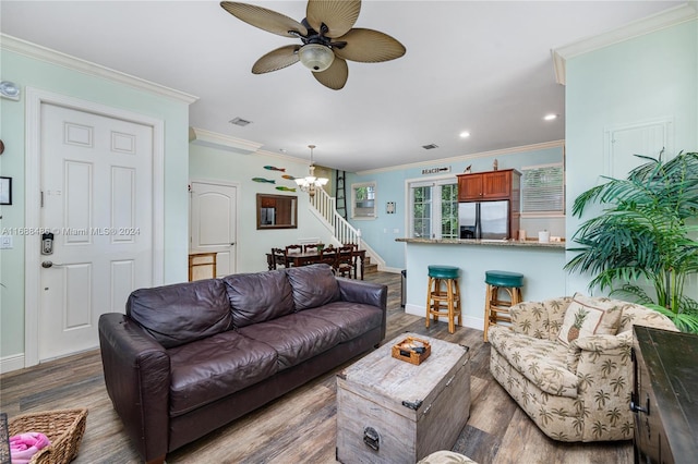 living room featuring ceiling fan with notable chandelier, hardwood / wood-style flooring, and crown molding