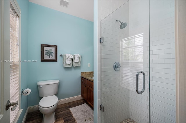 bathroom featuring a healthy amount of sunlight, walk in shower, hardwood / wood-style floors, toilet, and vanity