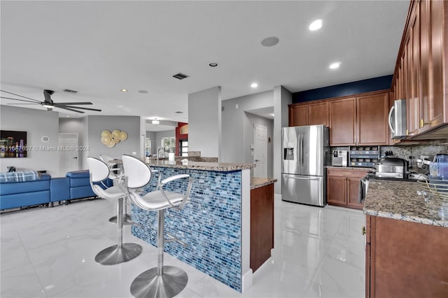 kitchen featuring a breakfast bar area, stainless steel appliances, stone counters, and tasteful backsplash