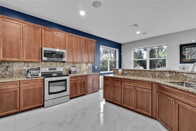 kitchen featuring tasteful backsplash, light stone countertops, sink, and stainless steel appliances