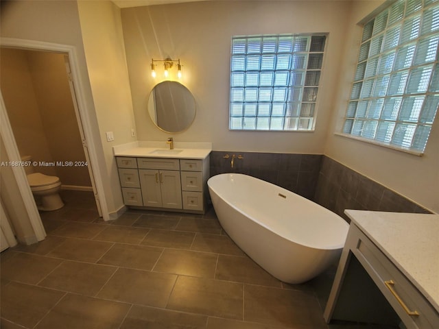 bathroom featuring tile patterned floors, vanity, a healthy amount of sunlight, and a washtub