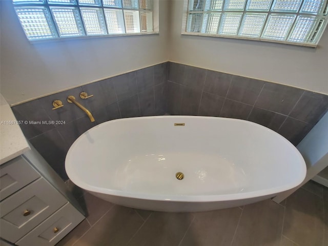 bathroom with tile patterned floors, a tub to relax in, and vanity