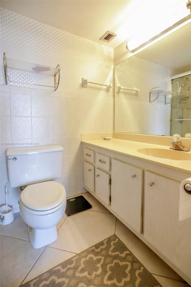 bathroom with vanity, tile patterned flooring, toilet, walk in shower, and tile walls