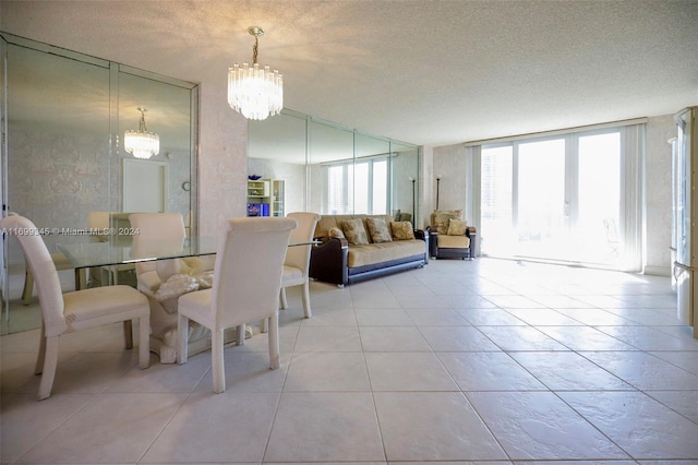 dining area featuring light tile patterned floors, a chandelier, a textured ceiling, and a wall of windows