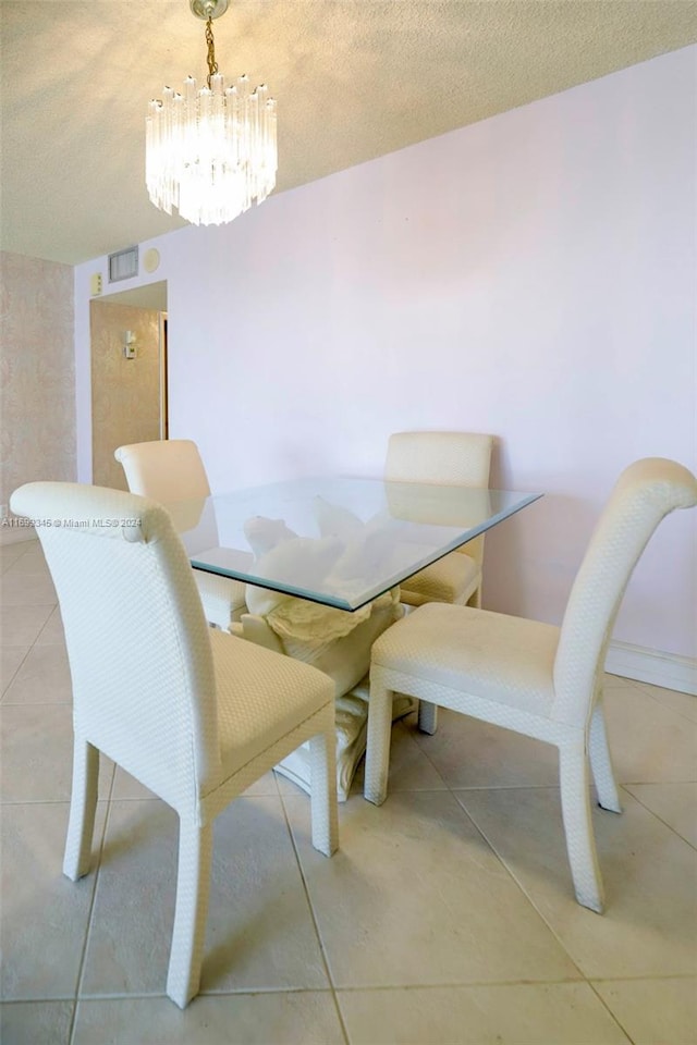 tiled dining space with a chandelier and a textured ceiling