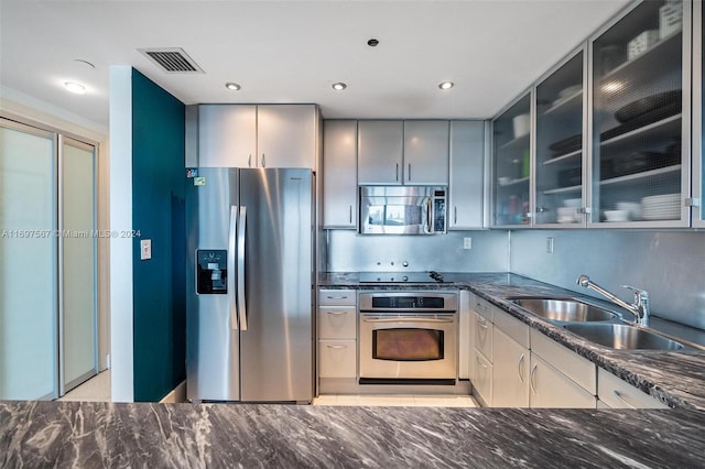 kitchen with dark stone countertops, sink, gray cabinetry, and appliances with stainless steel finishes