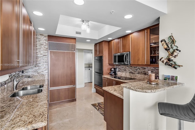 kitchen featuring a kitchen bar, kitchen peninsula, black appliances, and sink