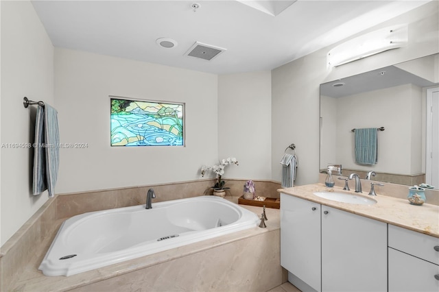 bathroom with vanity and tiled tub