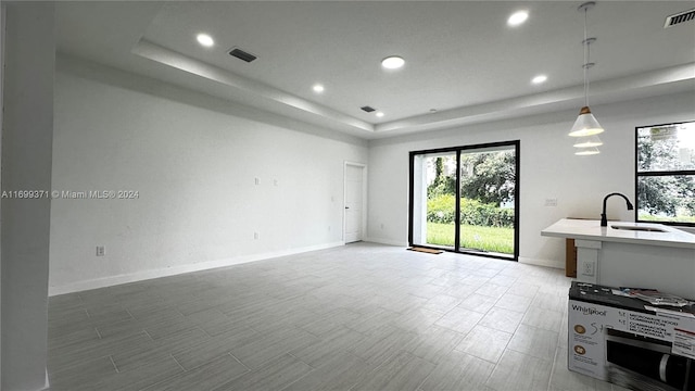 interior space featuring pendant lighting, a raised ceiling, and sink