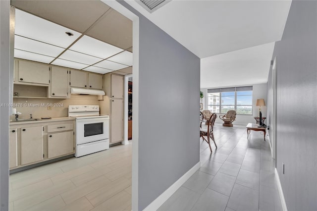 kitchen featuring cream cabinets, backsplash, white range with electric stovetop, and light tile patterned flooring