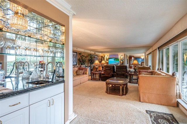 carpeted living room with crown molding, wet bar, and a textured ceiling