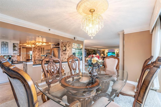 dining space featuring a textured ceiling, ornamental molding, a chandelier, and ornate columns