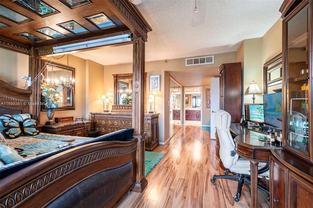 bedroom with an inviting chandelier, a textured ceiling, and light hardwood / wood-style flooring