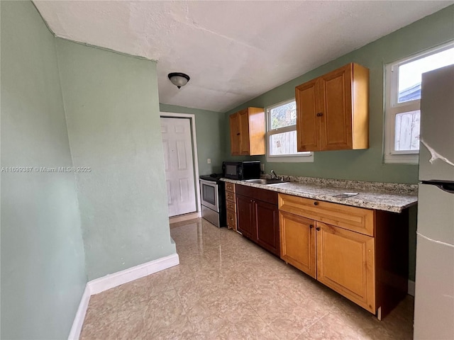 kitchen with fridge, stainless steel range with electric stovetop, and sink