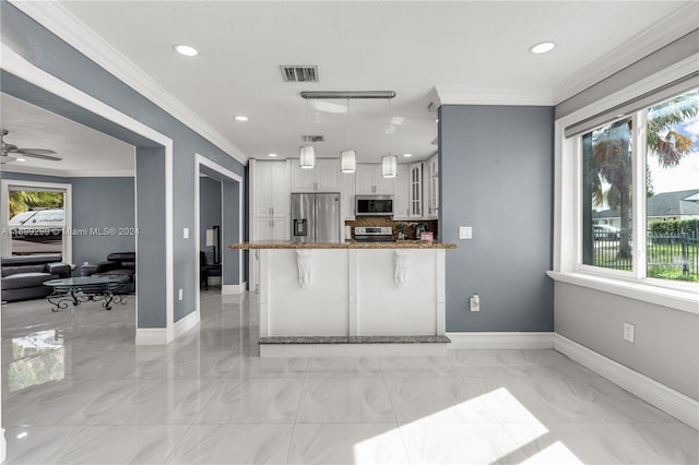 kitchen featuring kitchen peninsula, crown molding, decorative light fixtures, a kitchen bar, and appliances with stainless steel finishes