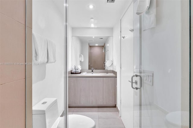 bathroom with tile patterned floors, vanity, an enclosed shower, and toilet