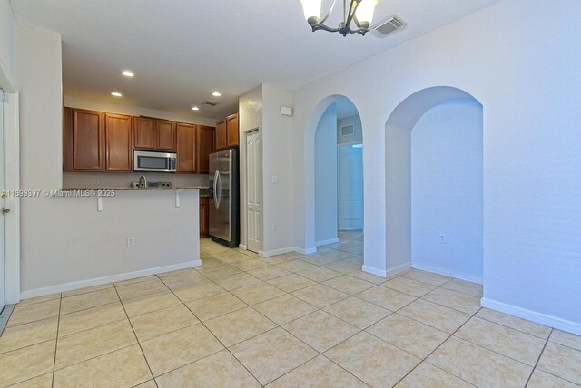 unfurnished room with light tile patterned flooring and an inviting chandelier