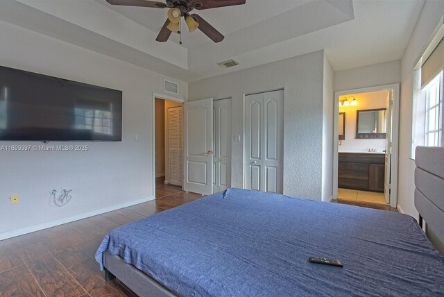 bedroom with a tray ceiling, ceiling fan, and dark wood-type flooring