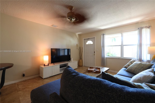 living room with ceiling fan, light tile patterned floors, and a textured ceiling