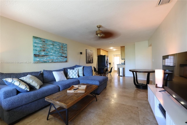 living room with a textured ceiling and ceiling fan