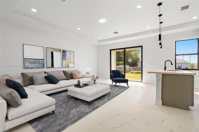 living room with a raised ceiling and sink