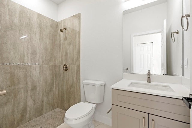 bathroom with a tile shower, vanity, and toilet