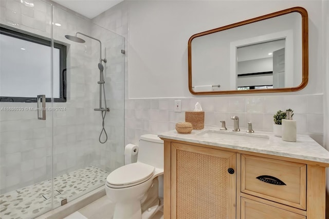 bathroom featuring vanity, toilet, tile walls, and walk in shower