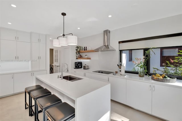 kitchen featuring black electric stovetop, white cabinetry, wall chimney exhaust hood, and sink