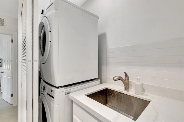 laundry area featuring stacked washer / dryer and sink