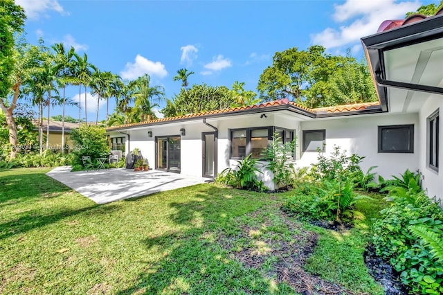 back of property with a patio area and a lawn