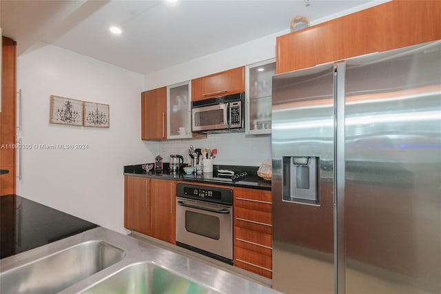 600 W Las Olas Blvd Unit 509S, Fort Lauderdale, FL 33312 - kitchen with stainless steel appliances, brown cabinetry, glass insert cabinets, dark countertops, and recessed lighting