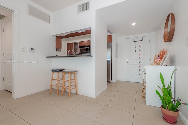 600 W Las Olas Blvd Unit 509S, Fort Lauderdale, FL 33312 - kitchen featuring light tile patterned floors, a kitchen bar, dark countertops, recessed lighting, and stainless steel appliances