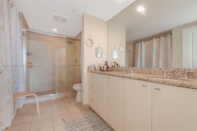 bathroom with tile patterned floors, a shower with door, vanity, and toilet