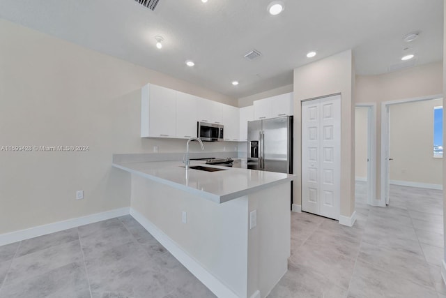 kitchen with kitchen peninsula, stainless steel appliances, sink, light tile patterned floors, and white cabinets