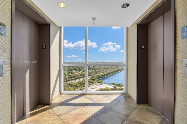 interior space featuring a water view, light tile patterned floors, and elevator