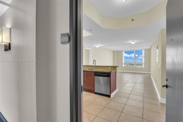 kitchen with light stone counters, light tile patterned floors, and stainless steel dishwasher