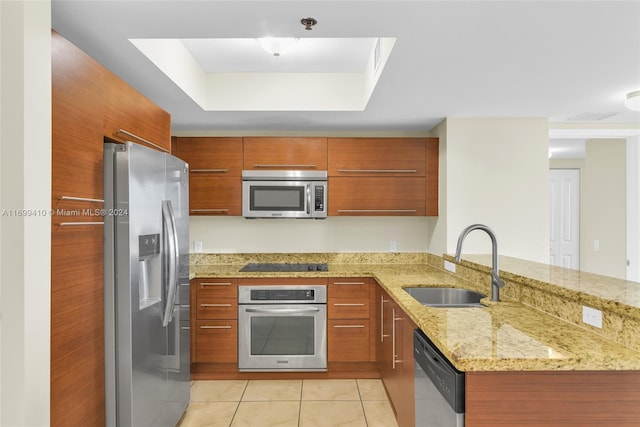 kitchen featuring light stone countertops, sink, kitchen peninsula, light tile patterned floors, and appliances with stainless steel finishes