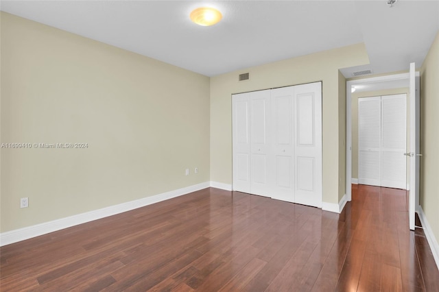 unfurnished bedroom with dark hardwood / wood-style flooring and a closet