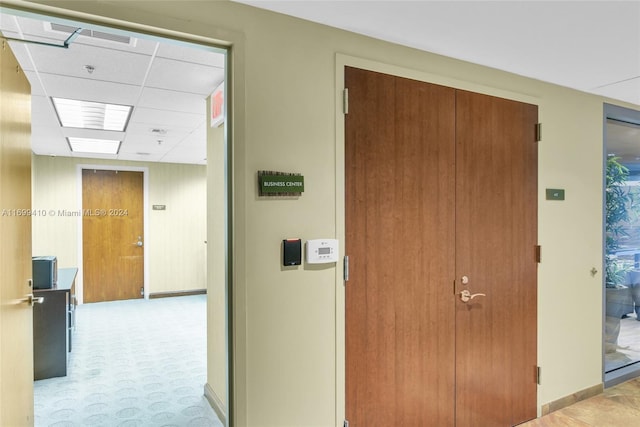 hall featuring a paneled ceiling and light colored carpet