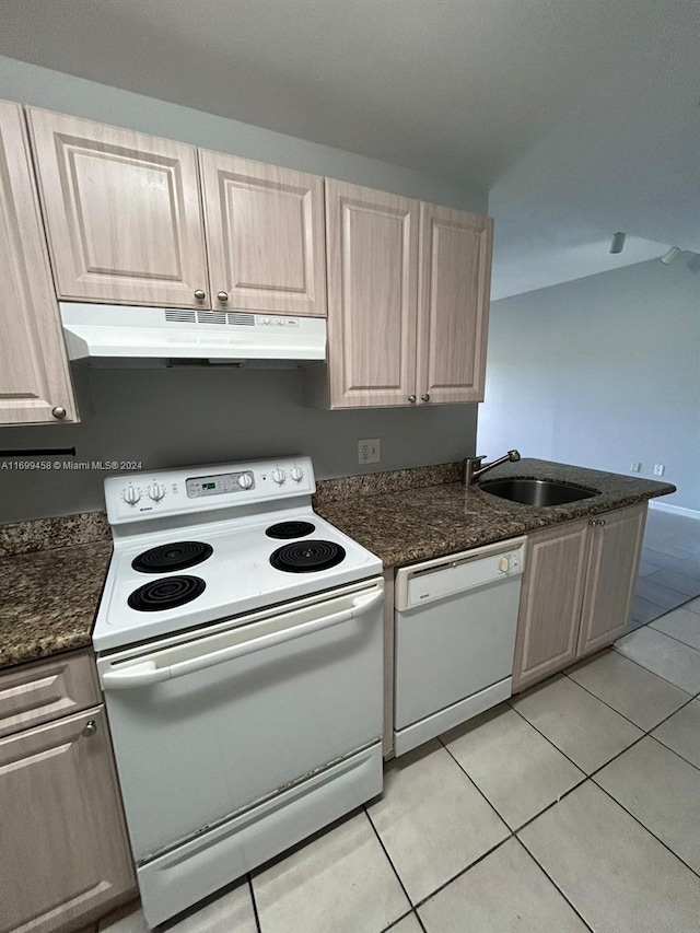 kitchen featuring sink, dark stone countertops, white appliances, light brown cabinetry, and light tile patterned flooring