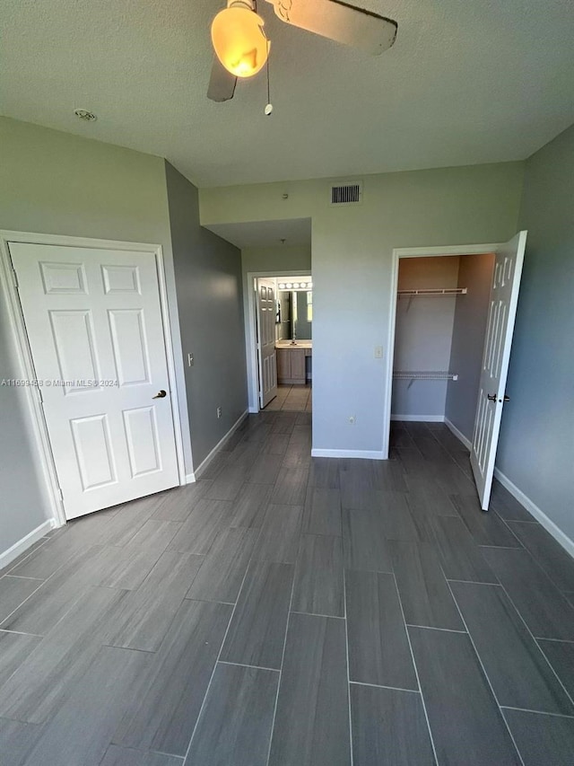 interior space featuring ceiling fan, a textured ceiling, connected bathroom, and a closet