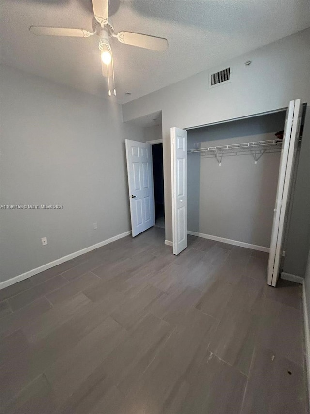 unfurnished bedroom featuring wood-type flooring, a textured ceiling, a closet, and ceiling fan