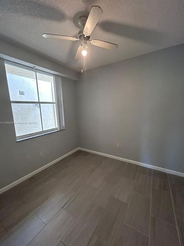 empty room with a textured ceiling, dark hardwood / wood-style flooring, and ceiling fan