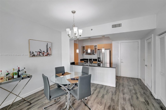 dining area with light wood-type flooring, sink, and an inviting chandelier