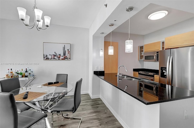 kitchen with sink, dark hardwood / wood-style floors, kitchen peninsula, decorative light fixtures, and appliances with stainless steel finishes