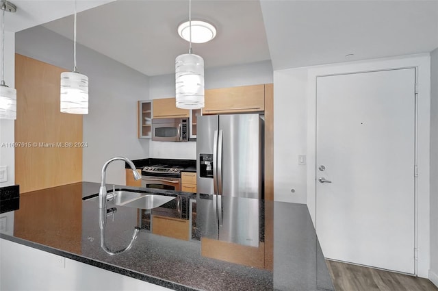 kitchen with pendant lighting, dark wood-type flooring, dark stone countertops, appliances with stainless steel finishes, and kitchen peninsula