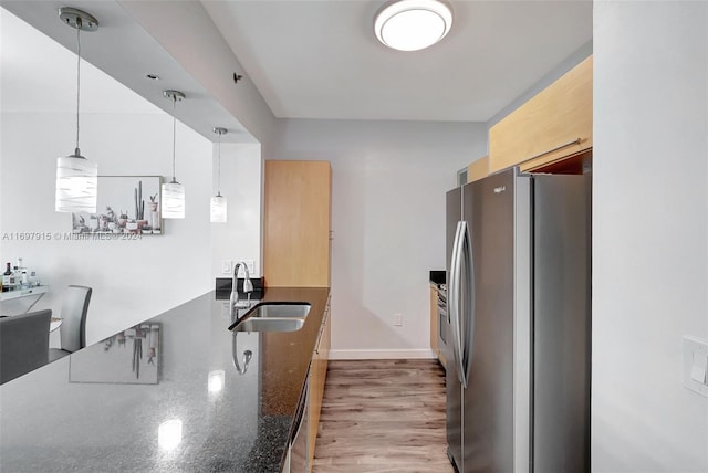 kitchen with stainless steel fridge, light wood-type flooring, pendant lighting, and sink