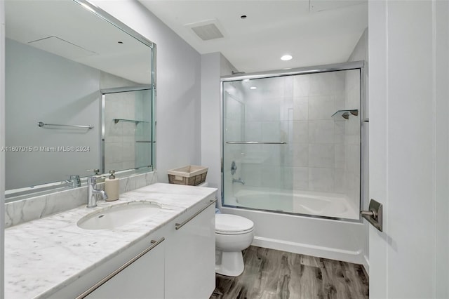 full bathroom with shower / bath combination with glass door, toilet, vanity, and hardwood / wood-style flooring